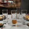 Alcohol being poured into 'Spirit Strength' branded shot glasses on a marble surface.